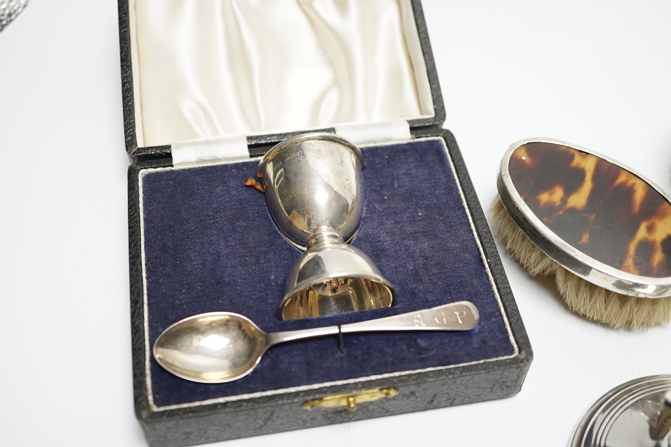 A cased silver christening egg cup and spoons and other items including nail buffers, inkwell, brushes etc.